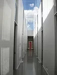 A red painted steel sculpture by Nigel Hall is visible at the end of the long, skylit corridor.