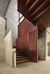 In the Pavilion wing, an ip' stair framed by walnut and chiseled-limestone walls connects the lower level to the lobby.