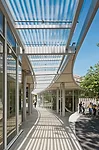 A fritted-glass canopy protects a breezeway from the full effects of the sun, providing a shaded path between the garden shop (right in photo) and the main building (left in photo).