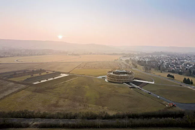 On the 91-acre site in Burgundy, France, the interpretation center echoes the ringed fortifications built by Julius Caesar in 52 b.c. A concrete gangway with wide, deep steps leads out to the partiall