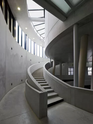 Some of the columns tilt in order to give the space a slightly less monumental air. The stairs swirl upward, with sidelights and top lights illuminating the space dramatically.