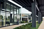 Steel canopies shade customers as they walk between the stores. Landscaping extends to these interstitial spaces.