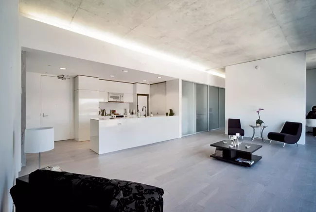 The exposed-concrete ceilings continue in the individual units. Services and mechanicals line one wall, freeing up the rest of the apartments for loftlike living. Partitions with sliding doors separat