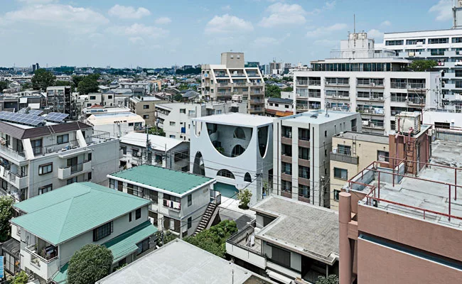 A curl of molded concrete connecting all four levels, a spiral stair stands on the building's south side'the most desirable place for an entrance in Japan. Mirroring the elliptical arches on the facad