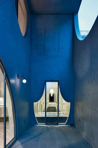 A playful, curtainlike window wall on the terrace relieves the concrete facade and frames views from the master bath.