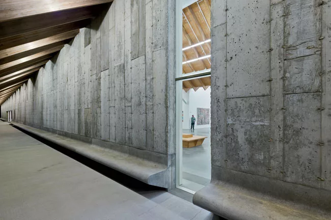 Outside, the concrete facade slopes out into a bench, allowing visitors to contemplate the landscape under the Parrish's deep eaves.