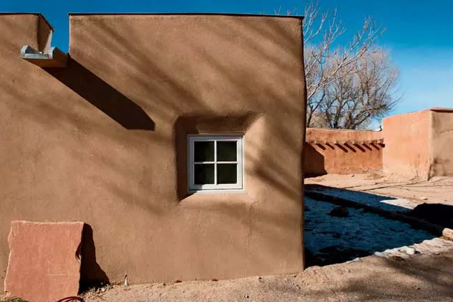 To improve the walls' durability, the client elected to incorporate elements such as metal caps on the roof parapets and flagstone splash blocks at the base of the walls under the <em>canales</em