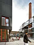 Children play on the Grande Cour of the former soap factory turned public-housing project, where an old chimney rises among new buildings and the remains of a 1950s warehouse are now a bilevel playgro