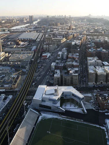 The building anchors the street corner while embracing the playing fields.