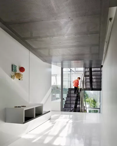 The transparency of the living spaces is accentuated by the balcony-like design of the living room and the perforated-steel stair.