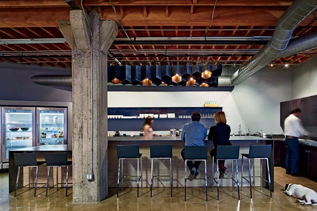 The architects used folded steel plate for the kitchen's island as well as for its light fixture, which they digitally fabricated in hexagons that recall the six-sided nut in Heavybit's logo.