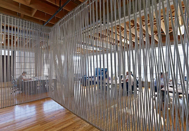 On the third floor the designers fashioned a breakout space from industrial rope and electrical conduit. They leavened the room's heavy look by suspending the curtain several inches above the floor.