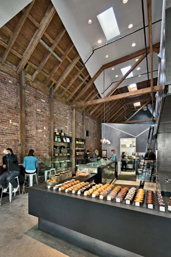 In a former autorepair shop, Zack | de Vito left the exposed brick walls and timber ceiling and inserted machine-age finishes for the kitchen and display areas.
