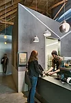 In a former autorepair shop, Zack | de Vito left the exposed brick walls and timber ceiling and inserted machine-age finishes for the kitchen and display areas