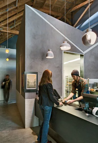 In a former autorepair shop, Zack | de Vito left the exposed brick walls and timber ceiling and inserted machine-age finishes for the kitchen and display areas