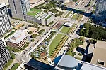 The at-grade park is heavily programmed with amenities ranging from a botanical garden with regional plants to a children's park with raised geofoam mounds covered in artificial turf.