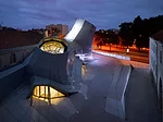The chimneys or snout-like forms gleam and light up at night. They are clad in lightweight panels of aluminum and resin perforated to accommodate LED lights designed by the firm Electronic Shadows.