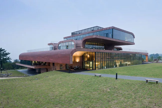 Nestled into the sloping site on an axis that will lead to other office buildings in the future, the 98,850-square-foot structure offers green roofs and a variety of outdoor spaces shaded by cantileve