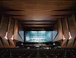 Oiled acacia wood panels lend a visual and acoustic richness to the concert hall. A cavity above the space accommodates lighting technicians as well as serving to draw smoke up and out of the space in