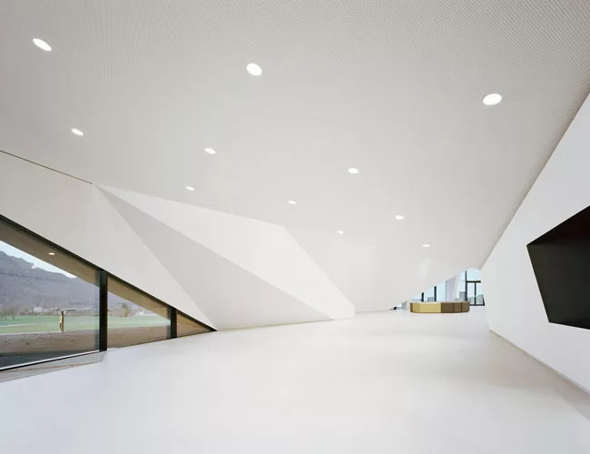 While referring to the surrounding mountain landscape as well as the building’s exterior, the foyer also serves as a counterpoint, with its bright white, crisply folded-plane walls and pristine,