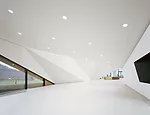 While referring to the surrounding mountain landscape as well as the building’s exterior, the foyer also serves as a counterpoint, with its bright white, crisply folded-plane walls and pristine,
