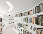 The collector's books are arranged on shelves along the back side of the major gallery wall, which is suspended from the existing ceiling's structure. The sinuously meandering space separates the gall