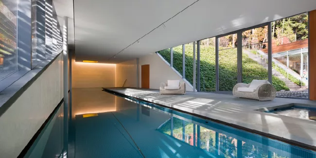 The recreation building features an interior lap pool, steam room, staff lounge, open living area, an interior courtyard, and an art gallery that connects the various spaces up to a second floor glass