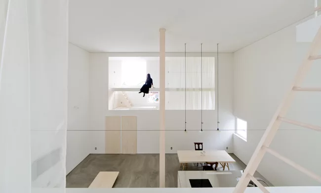 A staircase with treads of unpainted laurel wood leads from the ground level's concrete floor to the mezzanine levels above.