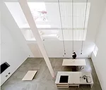 A staircase with treads of unpainted laurel wood leads from the ground level's concrete floor to the mezzanine levels above.