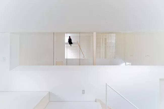 A staircase with treads of unpainted laurel wood leads from the ground level's concrete floor to the mezzanine levels above.