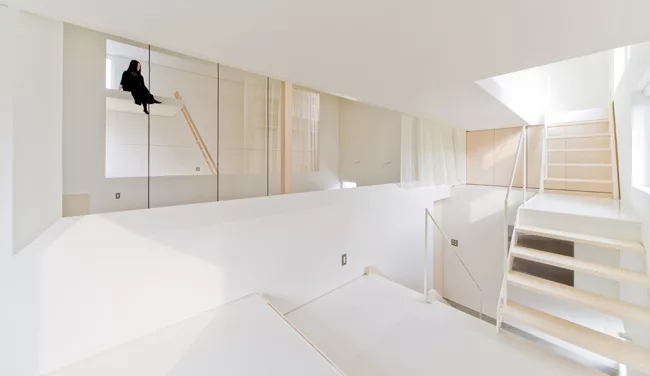 A staircase with treads of unpainted laurel wood leads from the ground level's concrete floor to the mezzanine levels above.