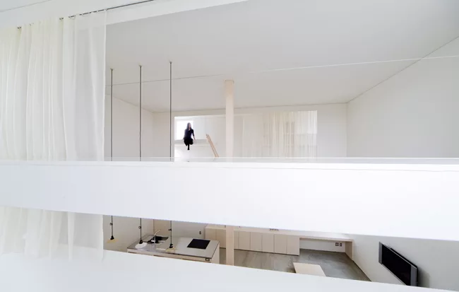 A staircase with treads of unpainted laurel wood leads from the ground level's concrete floor to the mezzanine levels above.