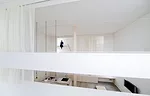 A staircase with treads of unpainted laurel wood leads from the ground level's concrete floor to the mezzanine levels above.