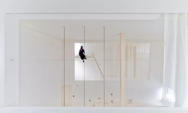 A staircase with treads of unpainted laurel wood leads from the ground level's concrete floor to the mezzanine levels above.