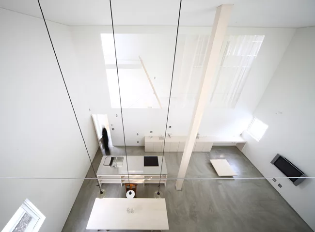A staircase with treads of unpainted laurel wood leads from the ground level's concrete floor to the mezzanine levels above.