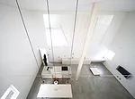 A staircase with treads of unpainted laurel wood leads from the ground level's concrete floor to the mezzanine levels above.