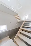A staircase with treads of unpainted laurel wood leads from the ground level's concrete floor to the mezzanine levels above.