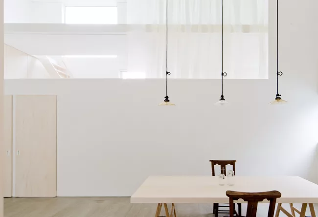 Light from the 'buffer zones' enters the central living area, which can be isolated by closing translucent white organdy curtains hanging on either of the space's long sides.