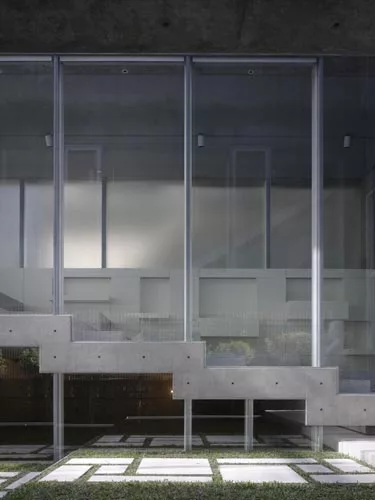 At the rear of the house, concrete decks and sectional cuts allow natural light to permeate the sitting area and an elevated dining space.
