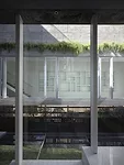 At the rear of the house, concrete decks and sectional cuts allow natural light to permeate the sitting area and an elevated dining space.