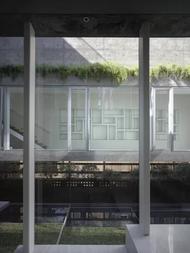 At the rear of the house, concrete decks and sectional cuts allow natural light to permeate the sitting area and an elevated dining space.