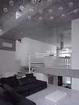 At the rear of the house, concrete decks and sectional cuts allow natural light to permeate the sitting area and an elevated dining space.