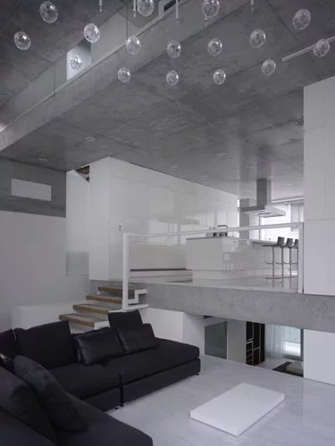 At the rear of the house, concrete decks and sectional cuts allow natural light to permeate the sitting area and an elevated dining space.