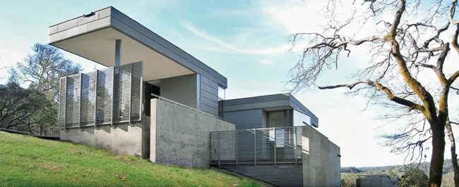 Concrete retaining walls nestle the house in a hill. The region is subject to landslides so the architects buried utilities and improved grading. 