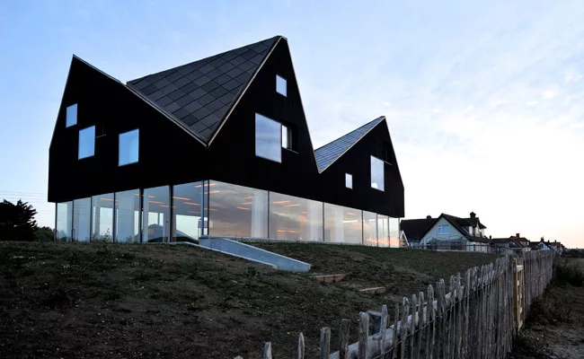 The jagged, timber-clad second story of the Dune House, on the east coast of England, contains bedrooms and bathrooms.