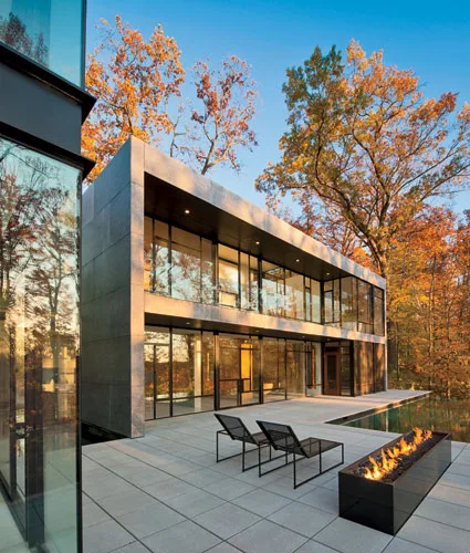 A formal living room and the master bedroom look out onto the infinity pool and woods from glass window walls.