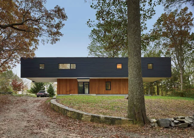 Clad in black-stained cedar, the upper story cantilevers 20 feet from each end.