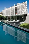 The perforated-metal screens on the third floor conceal balconies overlooking a basalt-edged lap pool.