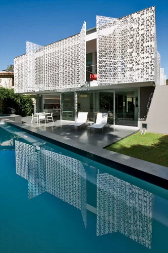 The perforated-metal screens on the third floor conceal balconies overlooking a basalt-edged lap pool.