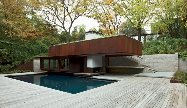 A board-formed-concrete retaining wall and stair lead to the pool house.
